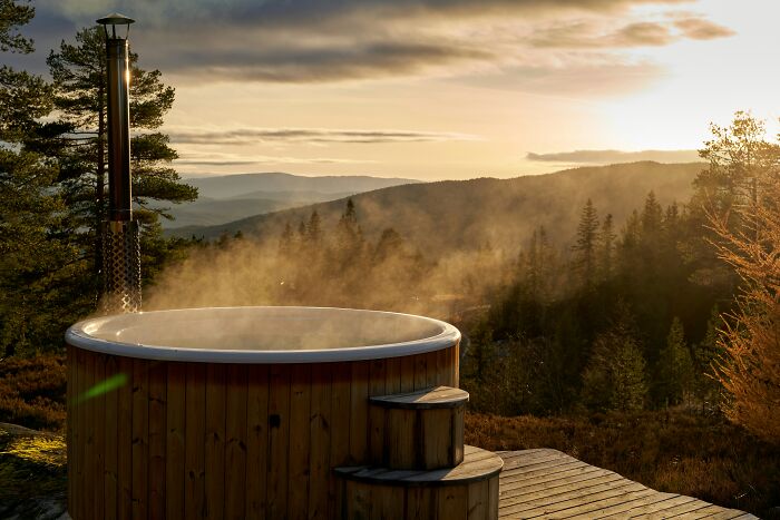 Guests enjoy a hot tub with a view of a serene mountain landscape at someone's home.