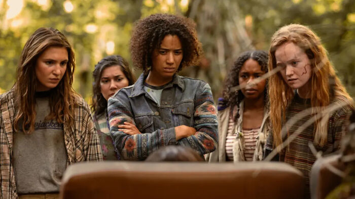 A group of women looking down, with one woman in the center wearing a denim jacket, symbolizing Hollywood's flawless-look obsession and unrealistic survival scenes. A group of women looking down, with one woman in the center wearing a denim jacket, symbolizing Hollywood's flawless-look obsession and unrealistic survival scenes.