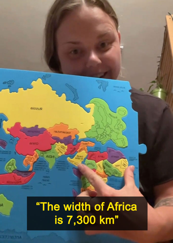 A woman pointing to Africa on a puzzle map, illustrating the actual scale of the continents, specifically Africa's width.