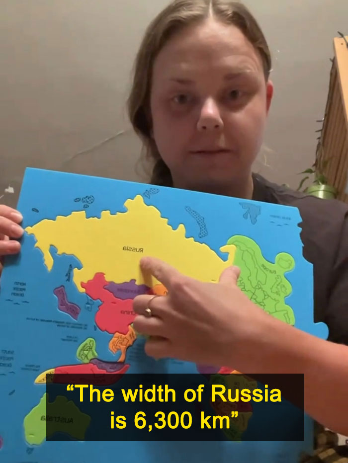 A woman pointing to Russia on a puzzle map, demonstrating the actual scale of the continents, specifically Russia's width.