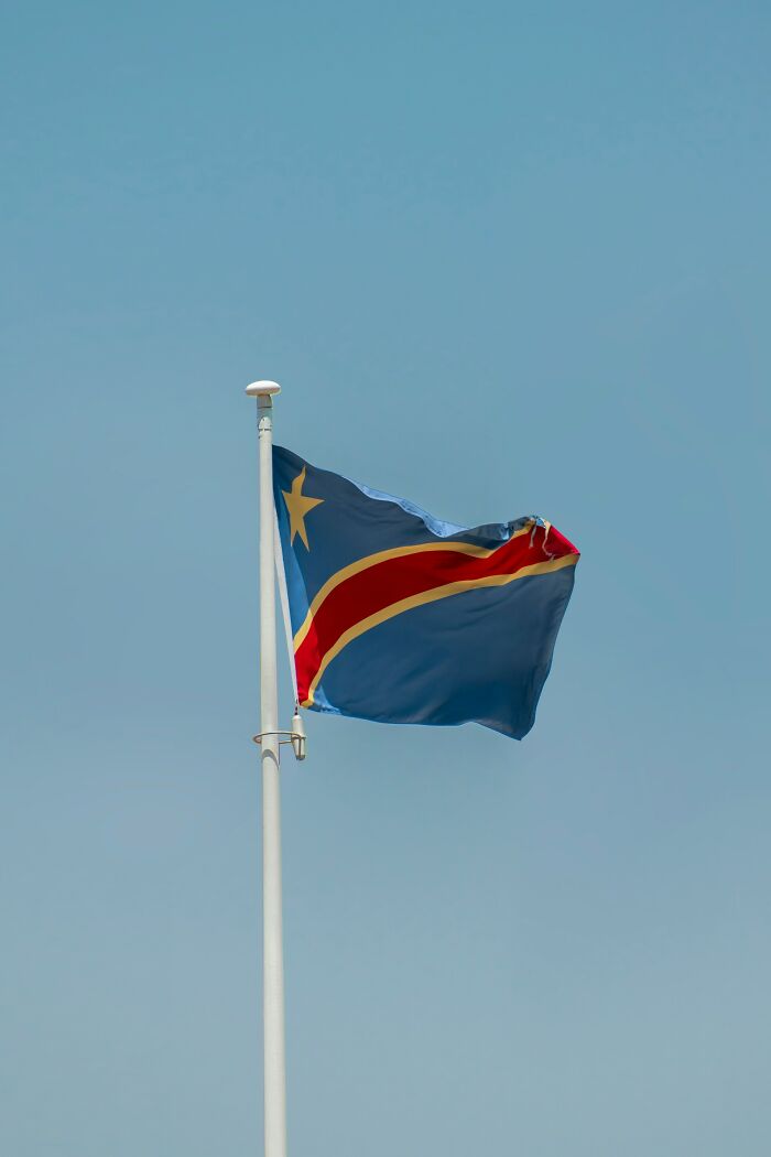 The flag of the Democratic Republic of Congo waving against a clear blue sky, showing fascinating things about the world.