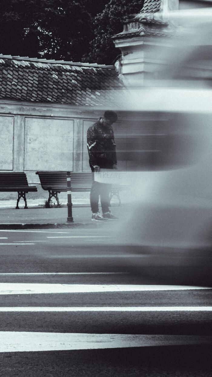 A person holding a sign by a road, capturing a disturbing public moment.