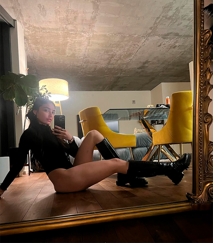 Adult star posing on the floor in a black leotard and boots, reflecting in a large ornate mirror, after winning a $3M payout. Adult star posing on the floor in a black leotard and boots, reflecting in a large ornate mirror, after winning a $3M payout.