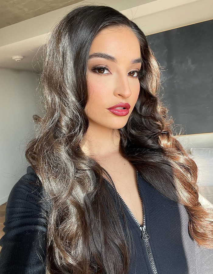 Adult star with long, dark curly hair and red lipstick, looking confidently at the camera, after winning a $3M payout. Adult star with long, dark curly hair and red lipstick, looking confidently at the camera, after winning a $3M payout.