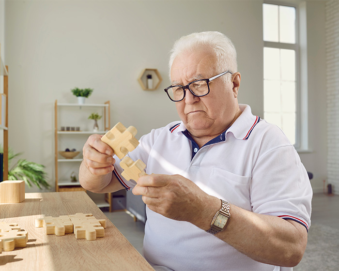 An older man concentrating on a wooden puzzle, relating to diagnosis and warning symptoms. An older man concentrating on a wooden puzzle, relating to diagnosis and warning symptoms.