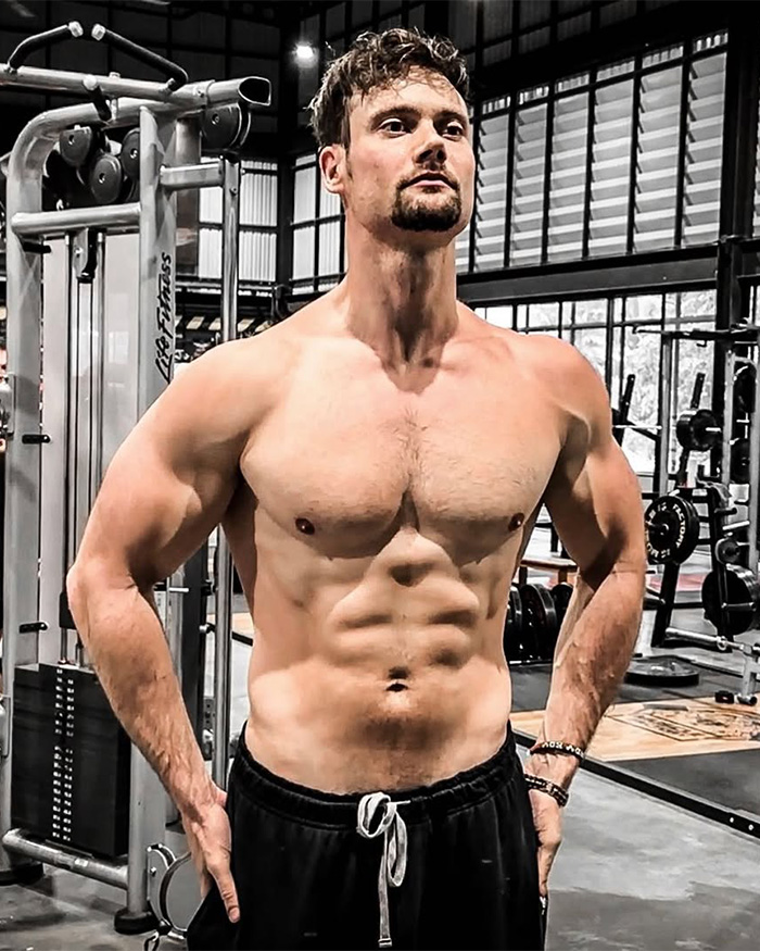 A lookmaxxer poses shirtless in a gym, highlighting his extreme transformation and muscular physique. A lookmaxxer poses shirtless in a gym, highlighting his extreme transformation and muscular physique.