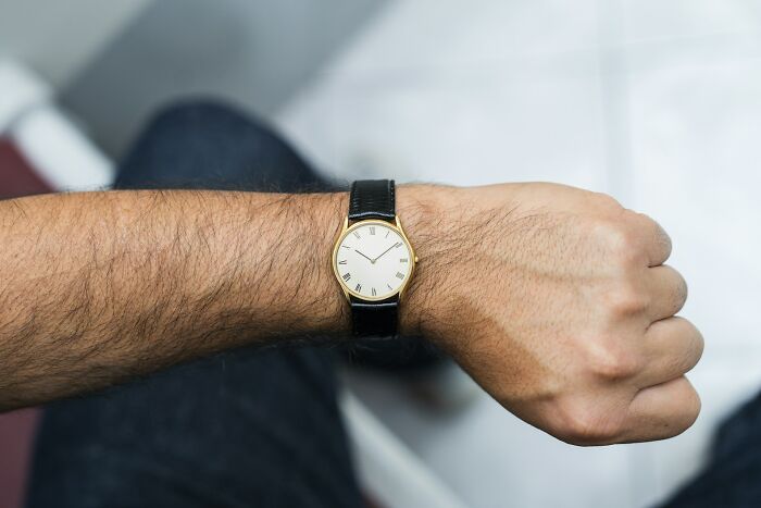 A man's wrist with a watch, symbolizing culture shocks and different perceptions of time with international partners.