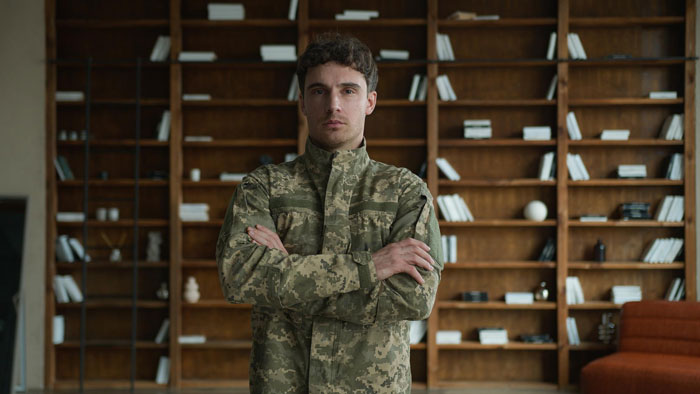Airsoft leader in camouflage uniform, arms crossed, standing in front of a bookshelf, reflecting the Airsoft dress code. Airsoft leader in camouflage uniform, arms crossed, standing in front of a bookshelf, reflecting the Airsoft dress code.
