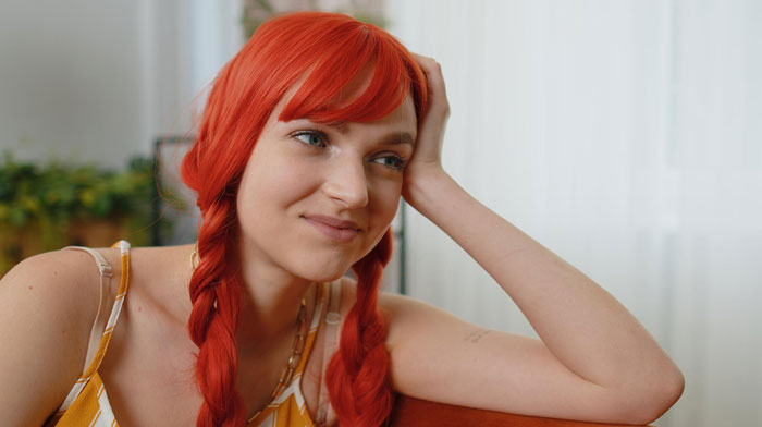 Close-up of a woman with bright red braided hair, smiling, symbolizing the airsoft dress code conflict. Close-up of a woman with bright red braided hair, smiling, symbolizing the airsoft dress code conflict.