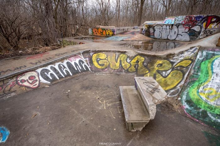 Urban explorers found an unexpected, abandoned skatepark covered in vibrant graffiti in a desolate, wooded area.
