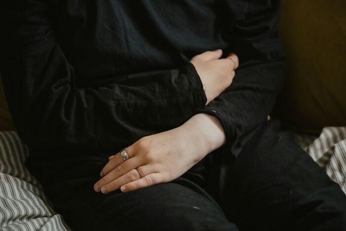 A person in black clothing with hands resting on their lap, symbolizing the frustration of mansplaining examples.