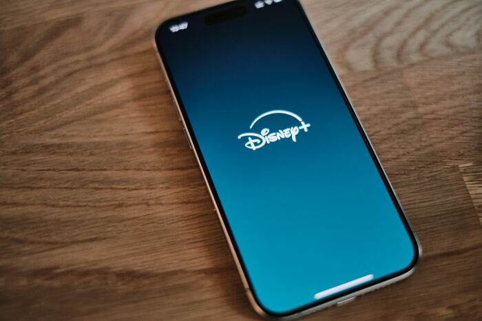 A smartphone displaying the Disney+ app, symbolizing entertainment choices among friends.