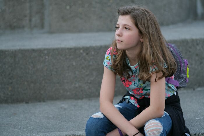 A young girl looking sad and thoughtful, experiencing a "we need to leave now" moment.