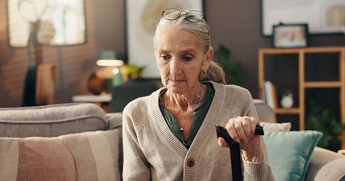 An elderly woman looks downcast, holding a cane, reflecting on being called unforgiving by her grandma about the wedding. An elderly woman looks downcast, holding a cane, reflecting on being called unforgiving by her grandma about the wedding.