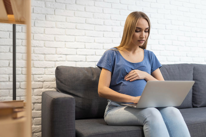 A pregnant woman, looking aghast, sits on a couch with a laptop, reflecting a situation where autism is an excuse. A pregnant woman, looking aghast, sits on a couch with a laptop, reflecting a situation where autism is an excuse.