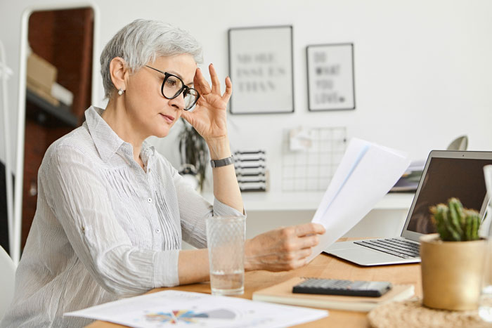 Woman with glasses looking stressed, holding papers, reflecting the sister's aghast reaction to her brother's autism excuse. Woman with glasses looking stressed, holding papers, reflecting the sister's aghast reaction to her brother's autism excuse.