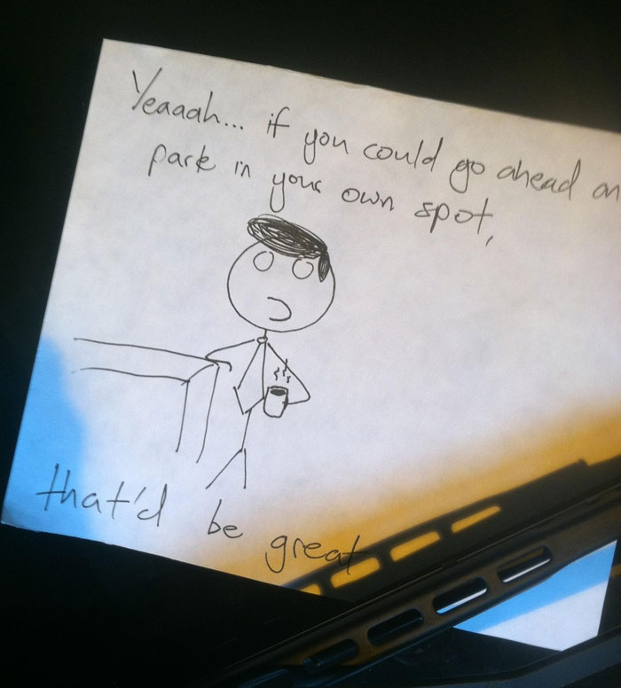 A note with a stick figure cartoon about outrageous parking, placed on a windshield.