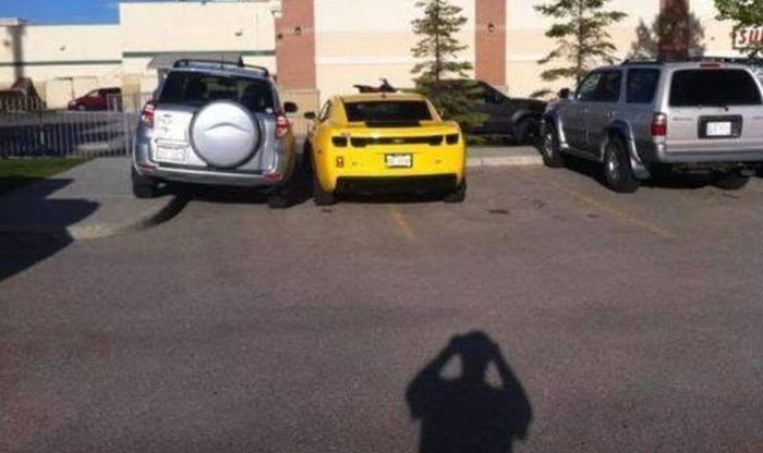 A yellow sports car and an SUV displaying outrageous parking in a parking lot.