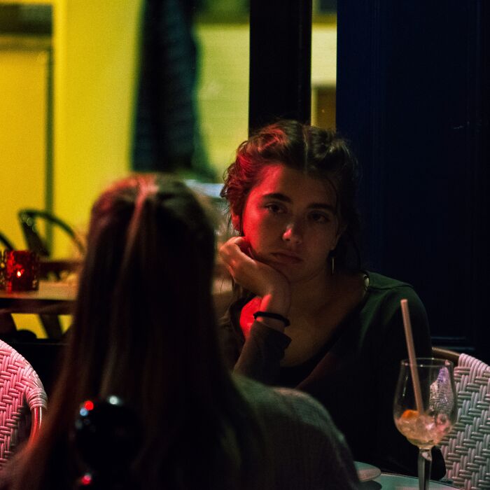 A woman looking intently across a table in a dark setting, illustrating conversations bartenders overheard.
