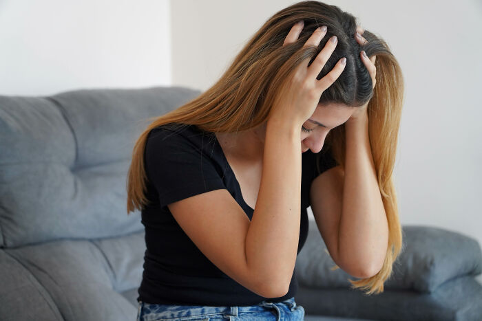 Bartenders overhear: a young woman holding her head, looking distressed, suggesting an emotional conversation.