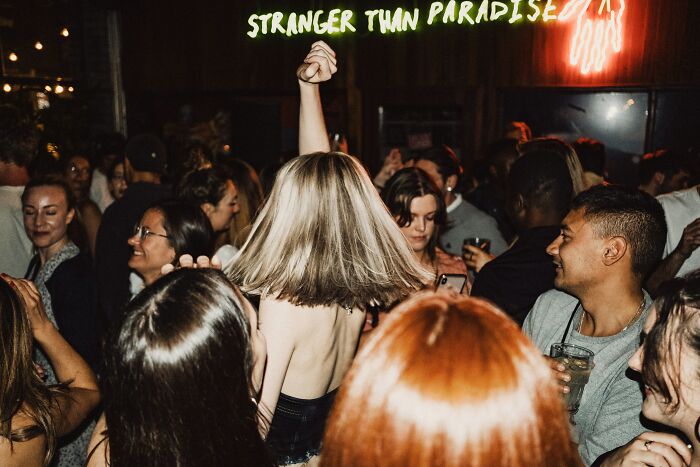 People dancing in a lively bar, suggesting the atmosphere where bartenders overhear wild conversations.