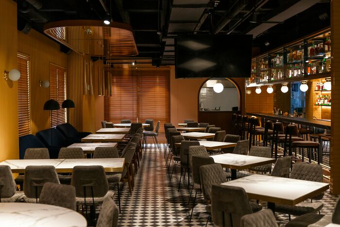 An empty bar with tables and a well-stocked bar, illustrating the setting for bartenders to overhear conversations.