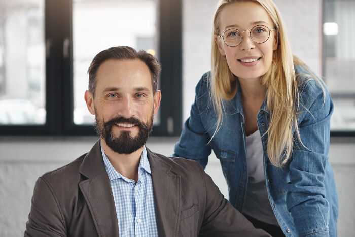 Two corporate workers smiling at the camera, symbolizing corporate practices and workplace culture.