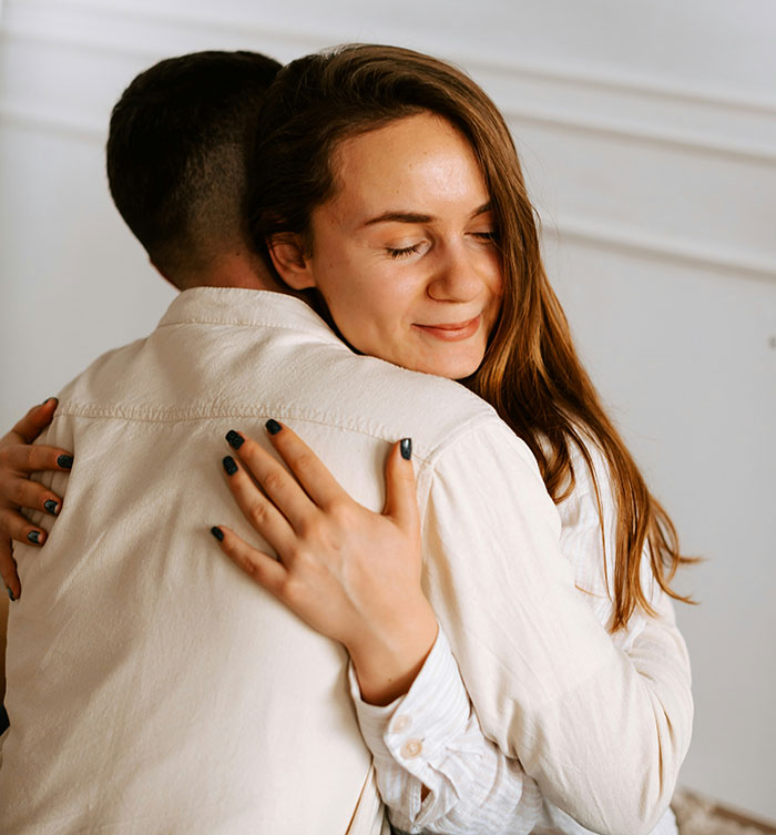 A young woman with long hair hugging a man from behind. Beautiful facts about relationships.
