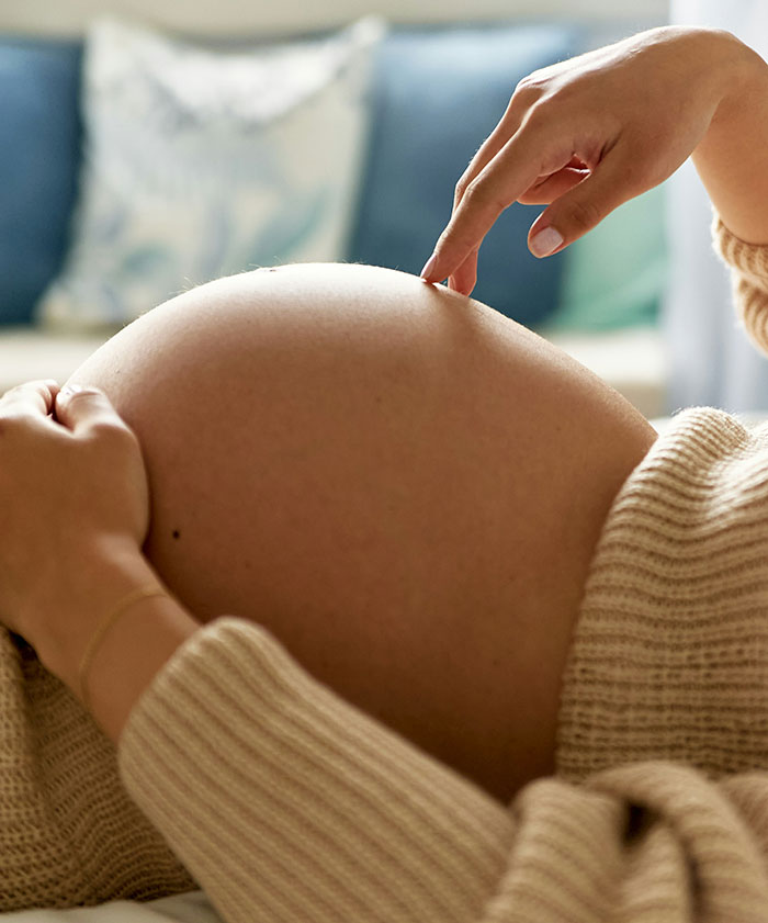 A pregnant woman gently touching her baby bump, illustrating beautiful facts about human life.