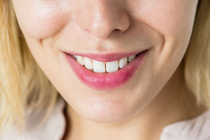 Close-up of a woman's smile with white teeth and pink lipstick, representing beautiful facts.