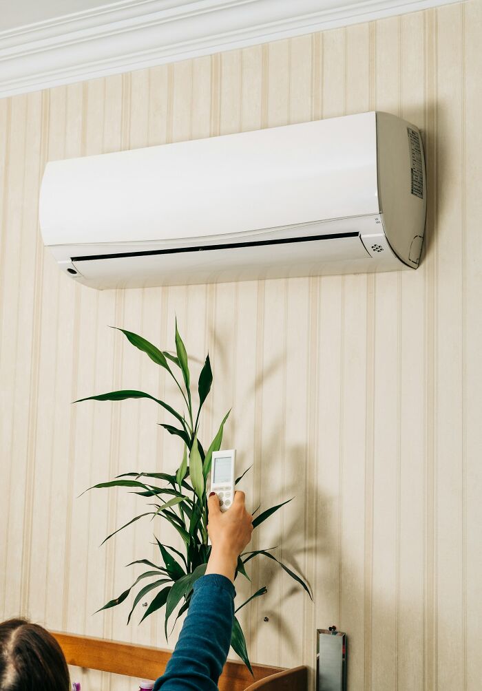 A person using a remote control for an air conditioner, illustrating common American habits.