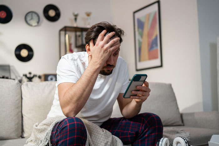 A man looking distressed at his phone, related to the groom's friend missing the wedding and withdrawal issues. A man looking distressed at his phone, related to the groom's friend missing the wedding and withdrawal issues.