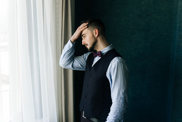 A groom's friend looking stressed while holding his head, contemplating the wedding and his withdrawal issues. A groom's friend looking stressed while holding his head, contemplating the wedding and his withdrawal issues.