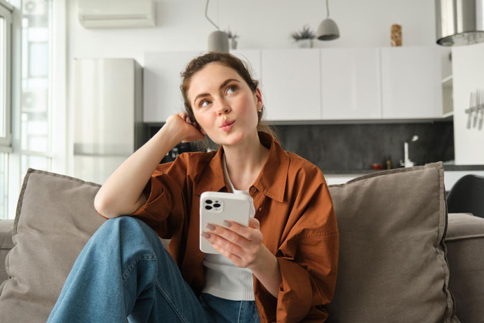 Woman pondering while holding a phone, reflecting on the guy's GF situation and shared details.