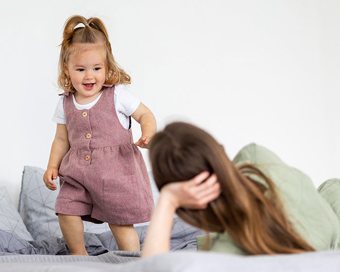 A happy toddler and a woman on a bed, illustrating the family aspects of a serial cheater and his secret kid. A happy toddler and a woman on a bed, illustrating the family aspects of a serial cheater and his secret kid.