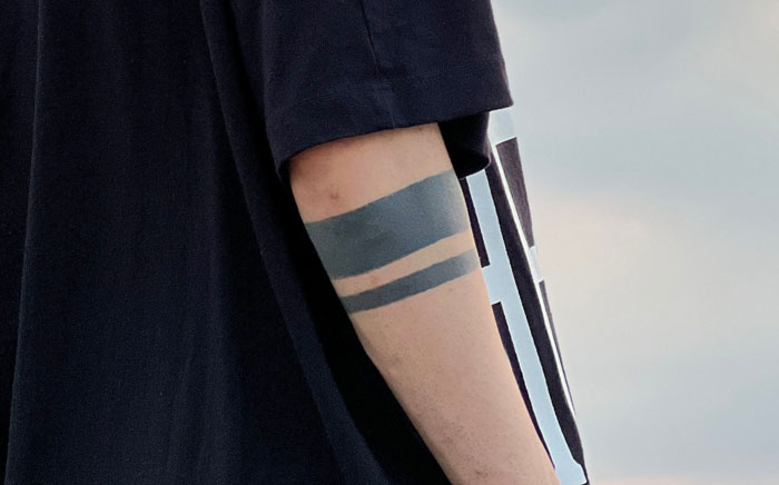 A person's arm with a double gray band tattoo, a requested tattoo in the industry.