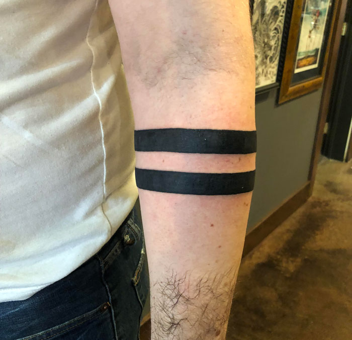 A person with a double black band tattoo on their forearm, a requested tattoo in the industry.