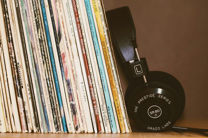A stack of legendary music artists and bands vinyl records with headphones on a shelf, highlighting the music alphabet. A stack of legendary music artists and bands vinyl records with headphones on a shelf, highlighting the music alphabet.