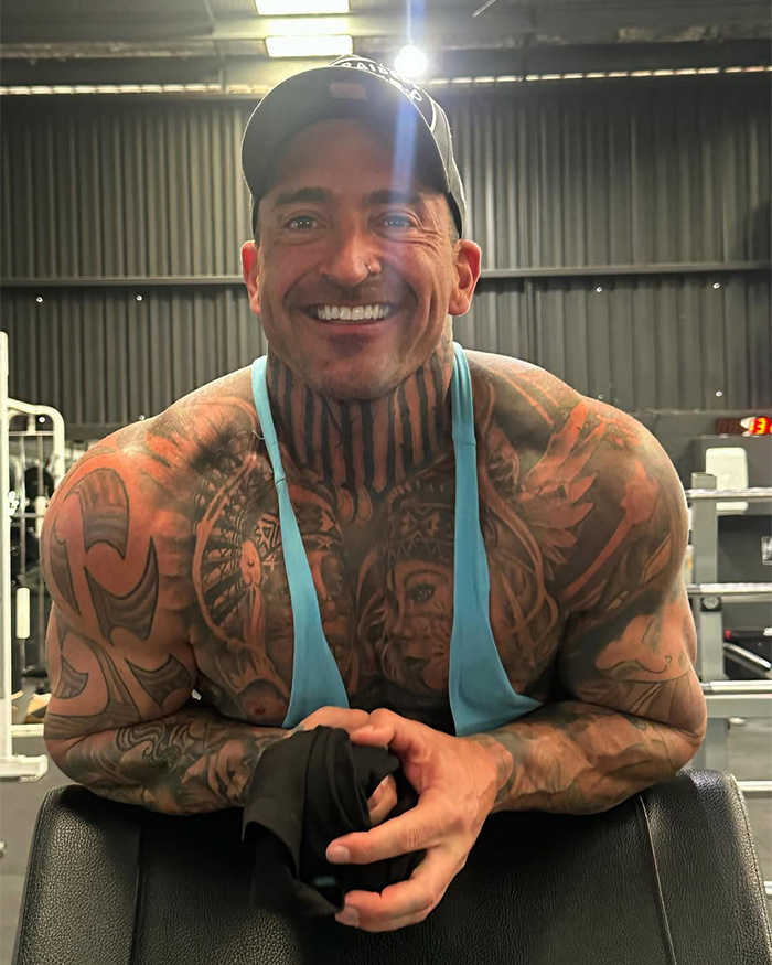 Muscular man with extensive tattoos, smiling, showcasing Bonnie Blue's life before fame.
