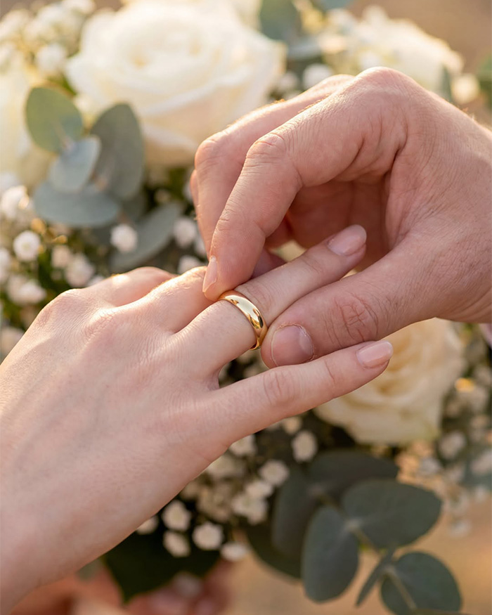 Close-up of a hand placing a wedding ring on another hand, amidst a baby shower scandal. Close-up of a hand placing a wedding ring on another hand, amidst a baby shower scandal.