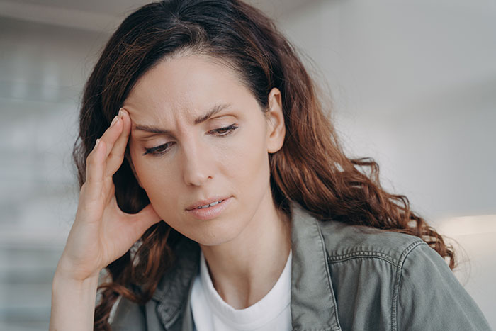 A distressed girlfriend, looking down and touching her forehead, confused and horrified after learning her guy pretends to be younger. A distressed girlfriend, looking down and touching her forehead, confused and horrified after learning her guy pretends to be younger.