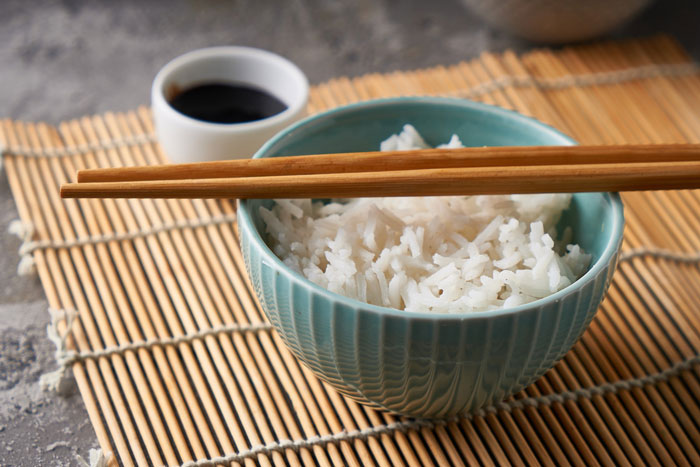 A bowl of white rice with chopsticks resting across it, alongside a small dish of soy sauce, reflecting chopstick etiquette. A bowl of white rice with chopsticks resting across it, alongside a small dish of soy sauce, reflecting chopstick etiquette.