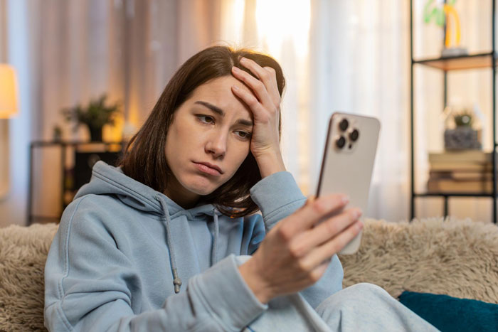 Woman looking upset while holding her phone, after BF deleting her phone app. Woman looking upset while holding her phone, after BF deleting her phone app.