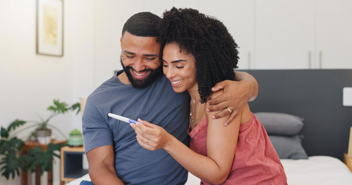 A happy couple embracing and smiling while looking at a positive pregnancy test, anticipating a new kid. A happy couple embracing and smiling while looking at a positive pregnancy test, anticipating a new kid.