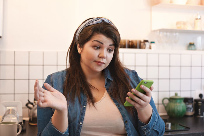 A confused woman looking at her phone, representing the impact of the groom's promise and bride's weight-based rejection. A confused woman looking at her phone, representing the impact of the groom's promise and bride's weight-based rejection.