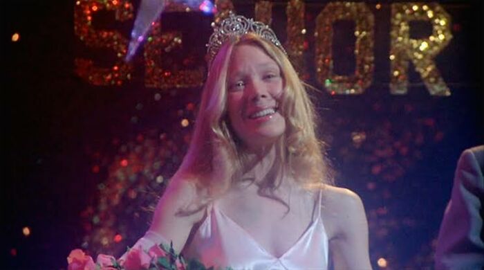 A girl in a tiara and white dress, looking emotional, in a scene from Stephen King's horror classic. A girl in a tiara and white dress, looking emotional, in a scene from Stephen King's horror classic.