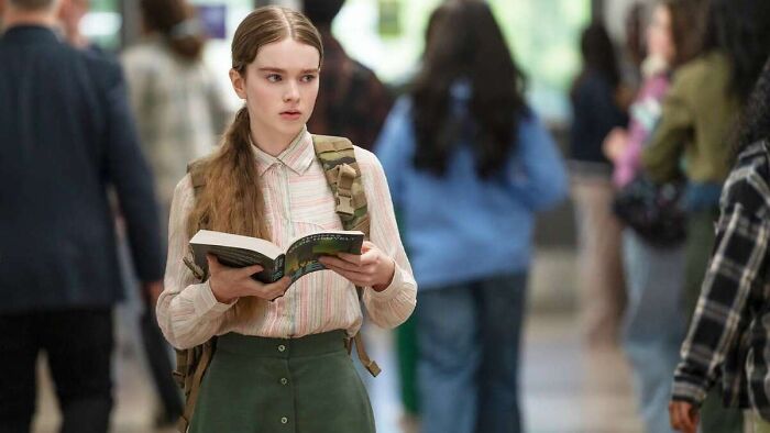 A young girl with long hair and a backpack, holding a book, in a shot of Stephen King's horror classic reboot. A young girl with long hair and a backpack, holding a book, in a shot of Stephen King's horror classic reboot.