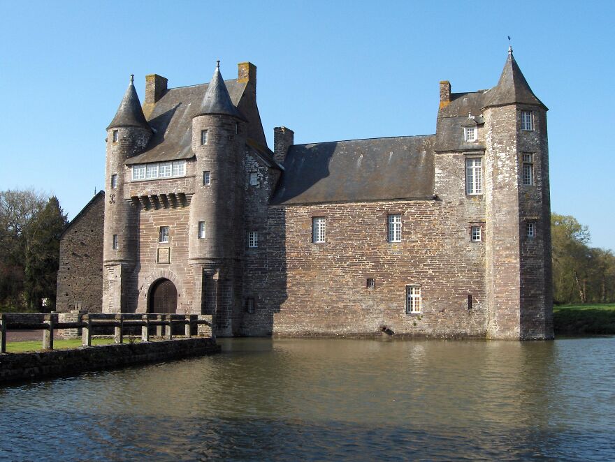 Beautiful stone castle with multiple turrets, surrounded by a calm body of water, offering an interesting historical view.