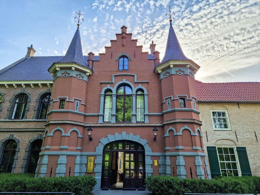 Beautiful and interesting red brick castle with turrets and intricate details under a partly cloudy sky.
