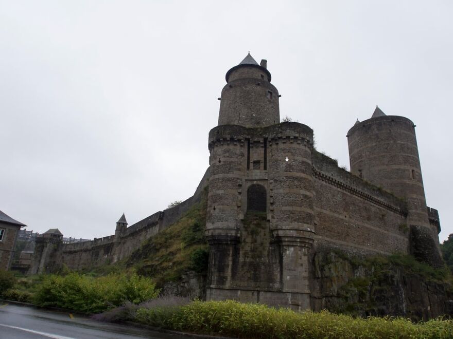 Beautiful old stone castle on a hill under an overcast sky, showcasing interesting architecture.